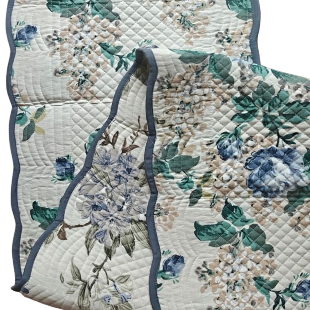 Quilted runner showing floral pattern and scalloped blue edging